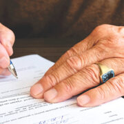 The hands of an old person signing a legal document