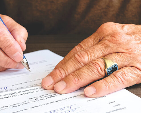 The hands of an old person signing a legal document
